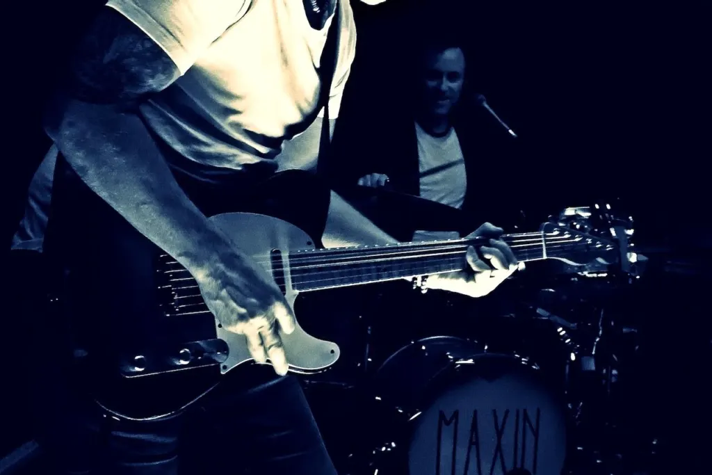 Gitarrist von MAXiN vor dem Bassdrum mit MAXiN-Logo