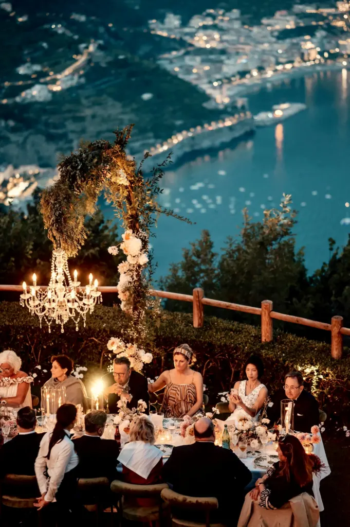 Hochzeitstafel mit Kronleuchter hoch über der beleuchteten Küste, Ravello, Italien
